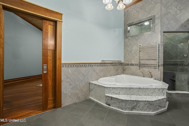 141 Janelle Dr, Bay Saint Louis, MS 39520 - bathroom featuring tile walls, a shower with door, radiator, a garden tub, and tile patterned floors