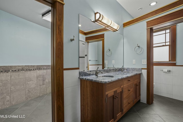 141 Janelle Dr, Bay Saint Louis, MS 39520 - bathroom featuring tile walls, tile patterned flooring, wainscoting, double vanity, and toilet