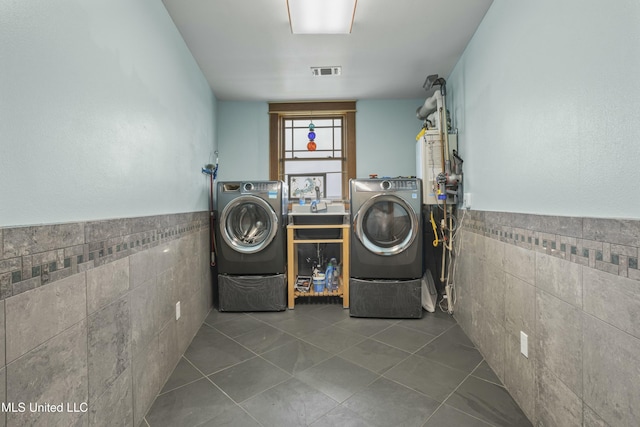 141 Janelle Dr, Bay Saint Louis, MS 39520 - laundry area with tile walls, washing machine and clothes dryer, tile patterned floors, and a wainscoted wall