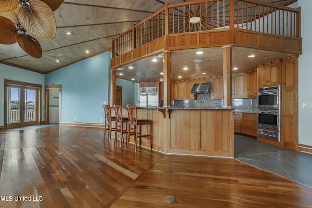 141 Janelle Dr, Bay Saint Louis, MS 39520 - kitchen featuring stainless steel appliances, a warming drawer, baseboards, high vaulted ceiling, and wall chimney exhaust hood