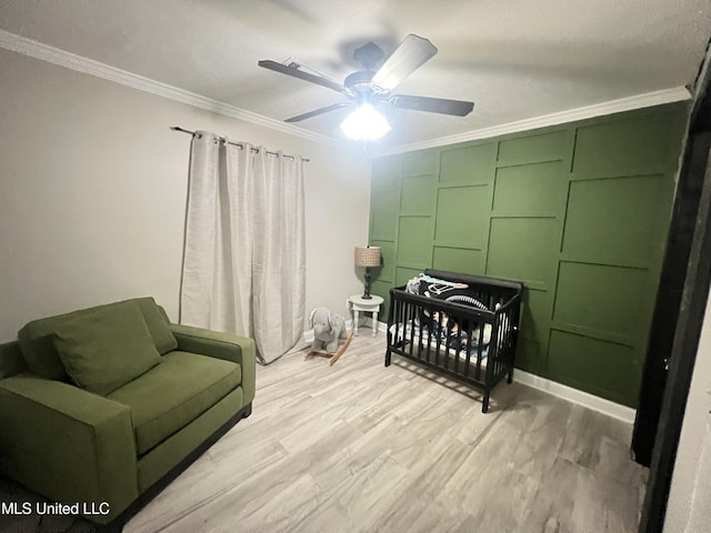 bedroom featuring ceiling fan, ornamental molding, light hardwood / wood-style flooring, and a crib