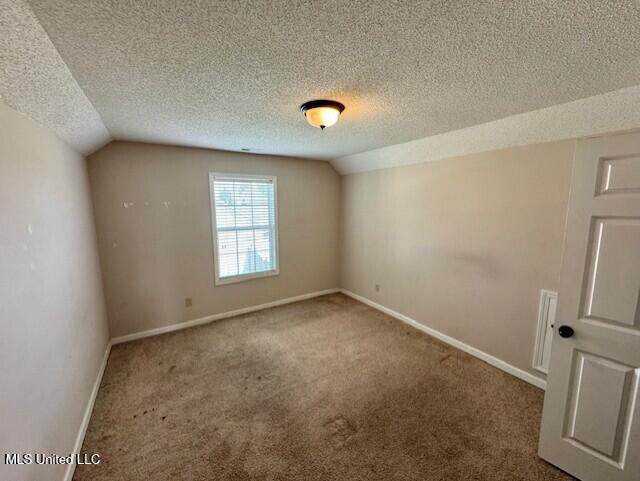 7428 Wallingford Dr, Olive Branch, MS 38654 - carpeted empty room featuring vaulted ceiling, a textured ceiling, and baseboards