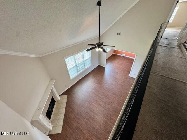 7428 Wallingford Dr, Olive Branch, MS 38654 - unfurnished living room featuring plenty of natural light, a tiled fireplace, ornamental molding, ceiling fan, and lofted ceiling