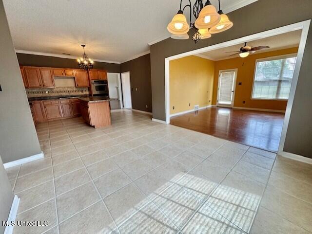 7428 Wallingford Dr, Olive Branch, MS 38654 - kitchen featuring a chandelier, open floor plan, stainless steel oven, crown molding, and light tile patterned floors