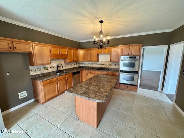 7428 Wallingford Dr, Olive Branch, MS 38654 - kitchen with stainless steel appliances, a sink, a chandelier, tasteful backsplash, and crown molding