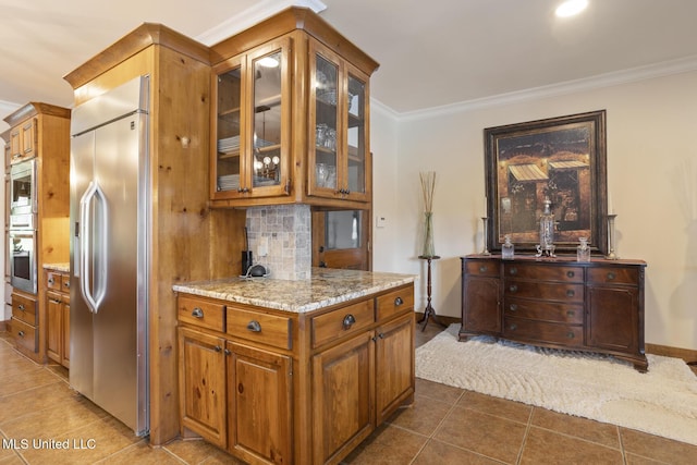 130 Pine Lake Cv, Flora, MS 39071 - kitchen featuring crown molding, brown cabinets, built in appliances, dark tile patterned flooring, and glass insert cabinets