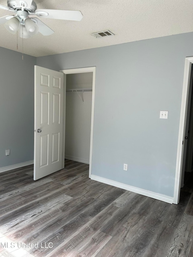 unfurnished bedroom featuring a textured ceiling, dark hardwood / wood-style floors, a closet, and ceiling fan