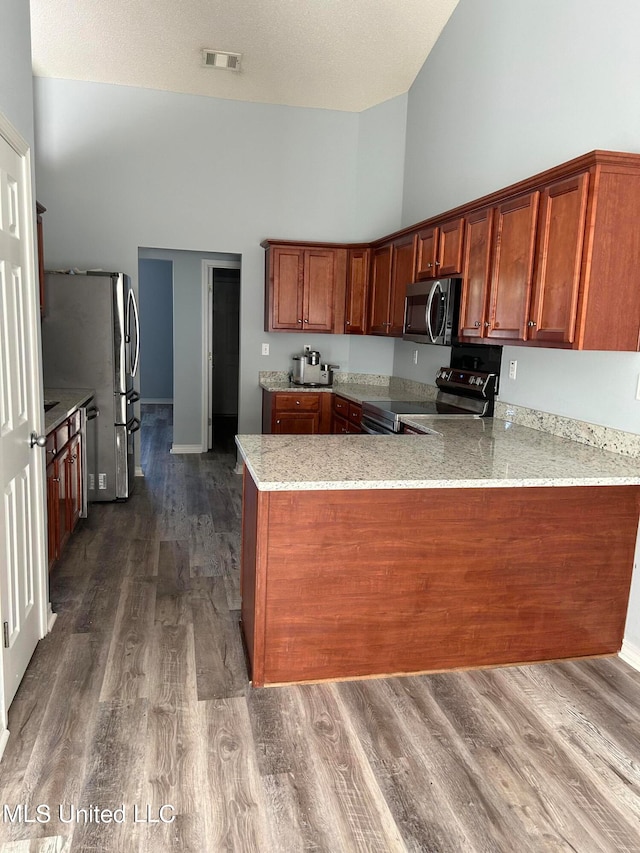 kitchen featuring high vaulted ceiling, kitchen peninsula, stainless steel appliances, and wood-type flooring