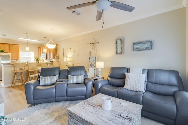 living room with ceiling fan, light hardwood / wood-style flooring, and crown molding