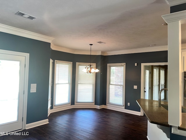 unfurnished dining area featuring ornamental molding, a textured ceiling, a notable chandelier, and dark hardwood / wood-style floors