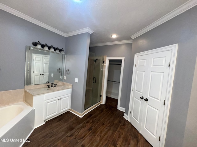 bathroom featuring hardwood / wood-style floors, vanity, plus walk in shower, and ornamental molding