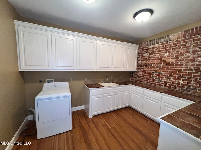 clothes washing area with cabinets, dark hardwood / wood-style flooring, sink, and washer / dryer