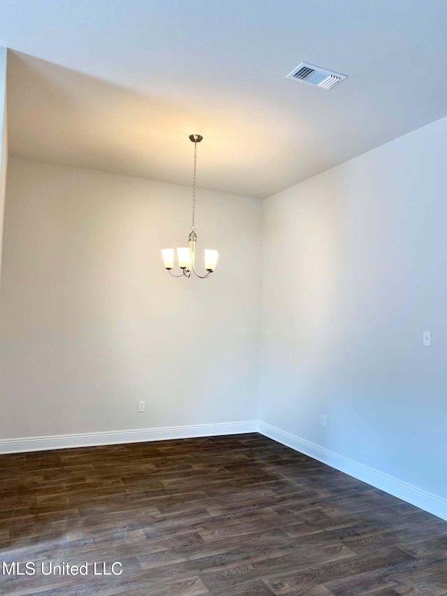 spare room with a notable chandelier and dark hardwood / wood-style floors