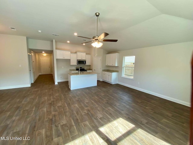 kitchen featuring white cabinetry, lofted ceiling, sink, a kitchen island with sink, and dark wood-type flooring