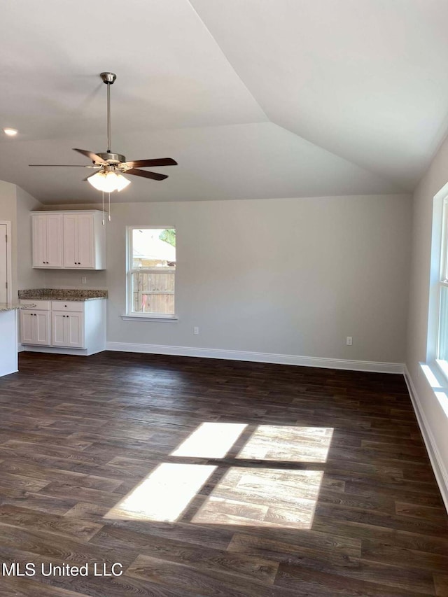 unfurnished living room featuring vaulted ceiling, dark wood-type flooring, and ceiling fan