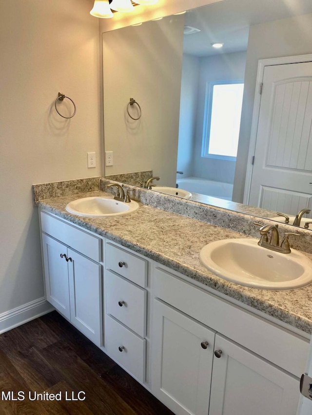 bathroom featuring hardwood / wood-style flooring, vanity, and a washtub