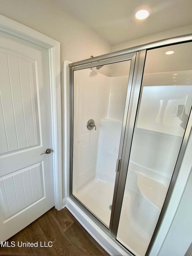 bathroom with wood-type flooring and an enclosed shower