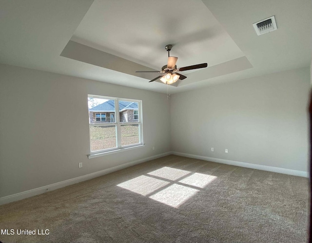 spare room featuring carpet floors, a raised ceiling, and ceiling fan