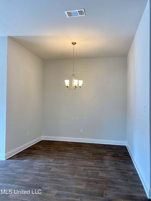 empty room with an inviting chandelier and dark hardwood / wood-style flooring