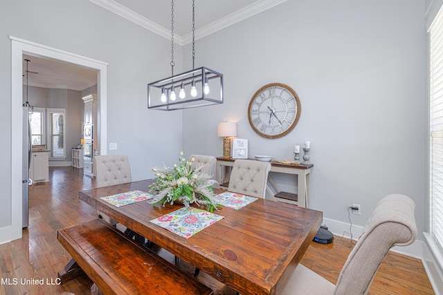 dining room with baseboards, wood finished floors, and crown molding