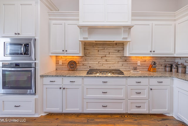 kitchen featuring appliances with stainless steel finishes, white cabinets, backsplash, and light stone countertops