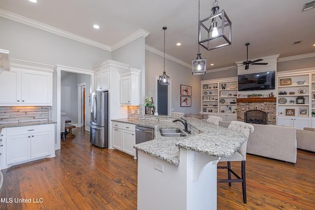 kitchen with a peninsula, a sink, a ceiling fan, white cabinetry, and appliances with stainless steel finishes