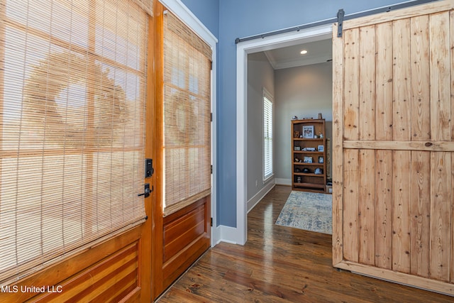 doorway with baseboards, a barn door, dark wood-style flooring, and crown molding