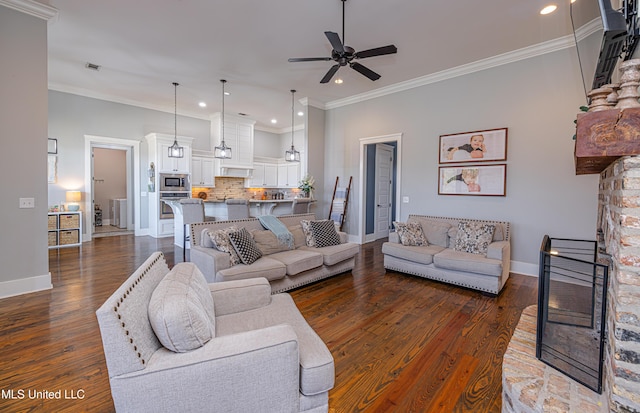 living room with baseboards, ceiling fan, ornamental molding, dark wood-style flooring, and a fireplace