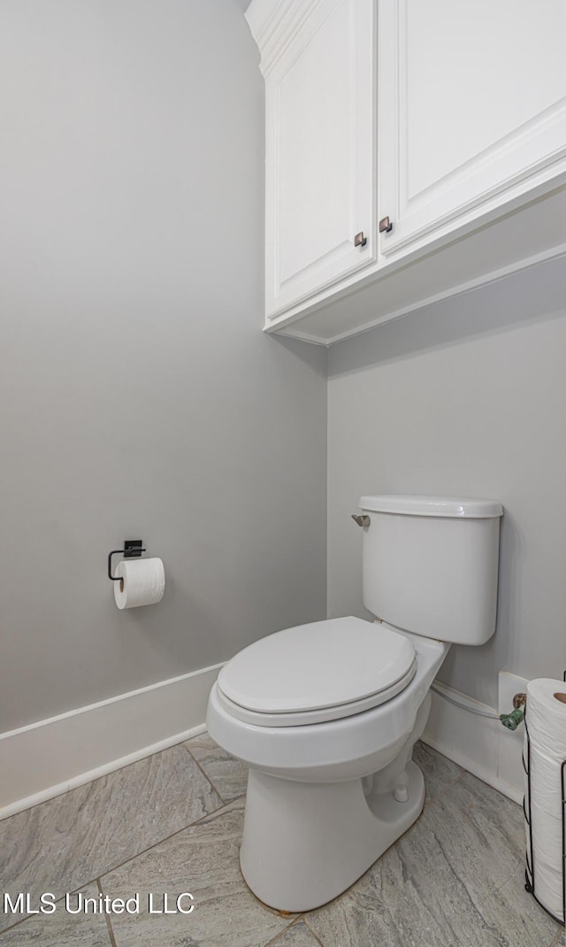 half bath with baseboards and toilet