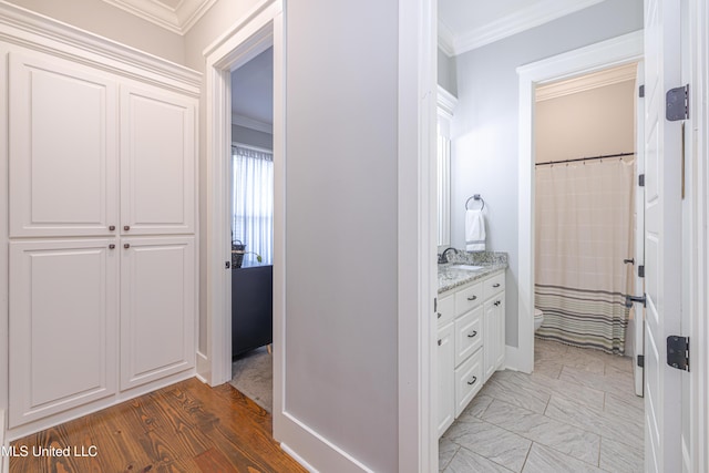 hall with light wood finished floors, ornamental molding, and a sink