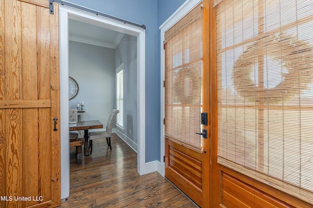 doorway with baseboards, a barn door, ornamental molding, and dark wood-style flooring