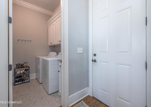 clothes washing area featuring baseboards, ornamental molding, cabinet space, and washer and dryer