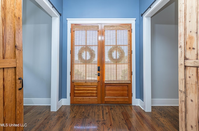 foyer with a barn door, baseboards, and dark wood-type flooring