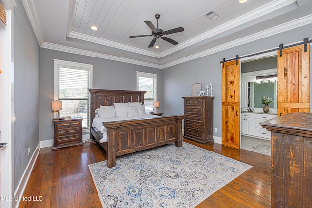 bedroom with a barn door, visible vents, baseboards, wood-type flooring, and crown molding