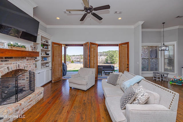 living room with visible vents, wood finished floors, crown molding, a brick fireplace, and recessed lighting