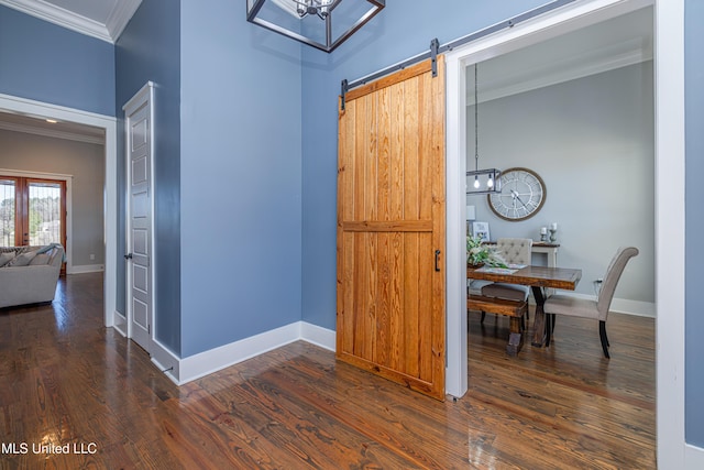 interior space with baseboards, a barn door, wood finished floors, and crown molding