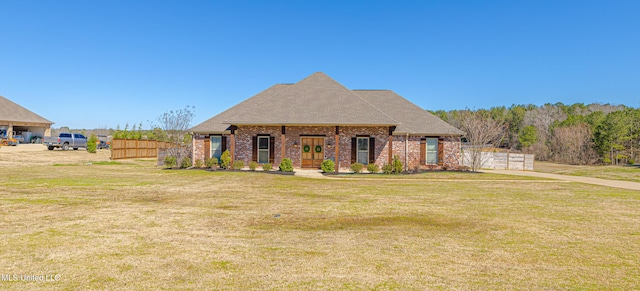 view of front facade featuring a front yard, french doors, brick siding, and fence