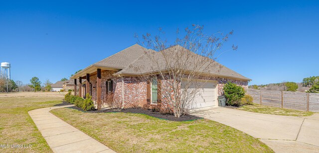 view of front of property featuring an attached garage, fence, a front lawn, and brick siding