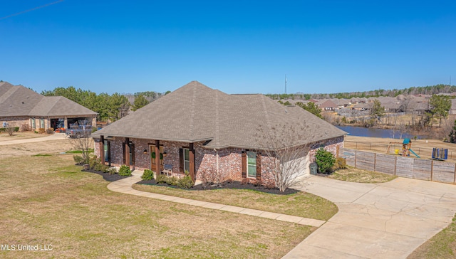 view of front of house with brick siding, a shingled roof, concrete driveway, an attached garage, and a front lawn