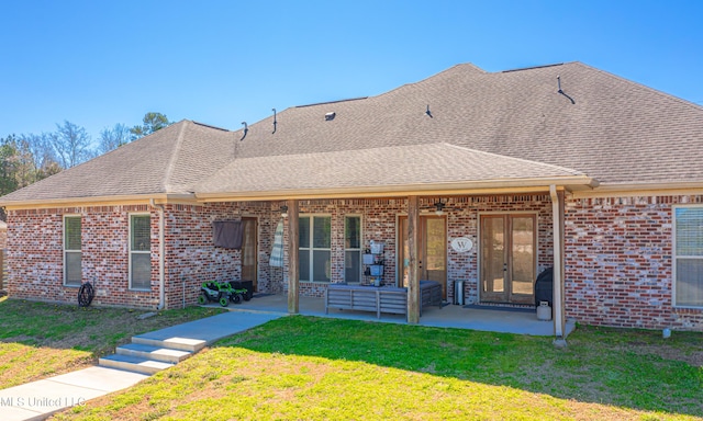 exterior space featuring french doors, a patio, roof with shingles, a yard, and brick siding