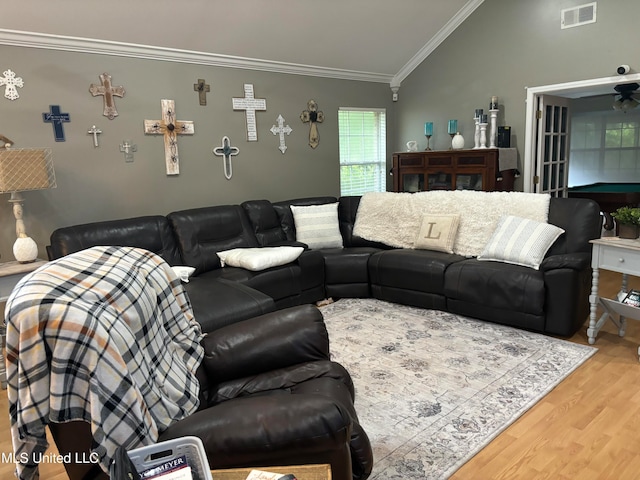 living area featuring visible vents, light wood-type flooring, lofted ceiling, and ornamental molding