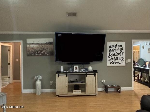 living area featuring visible vents, baseboards, wood finished floors, and ornamental molding