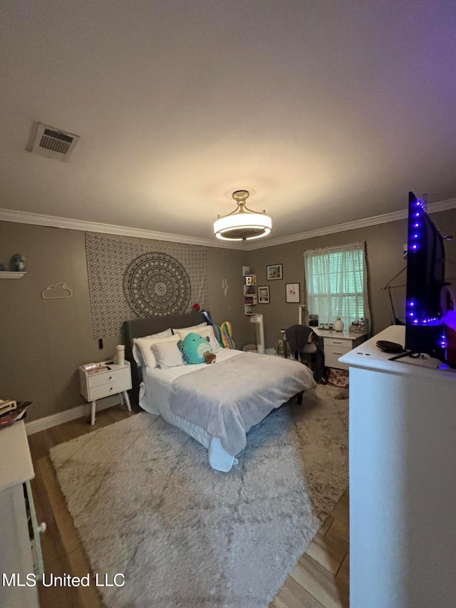 bedroom with visible vents, light wood-type flooring, crown molding, and baseboards