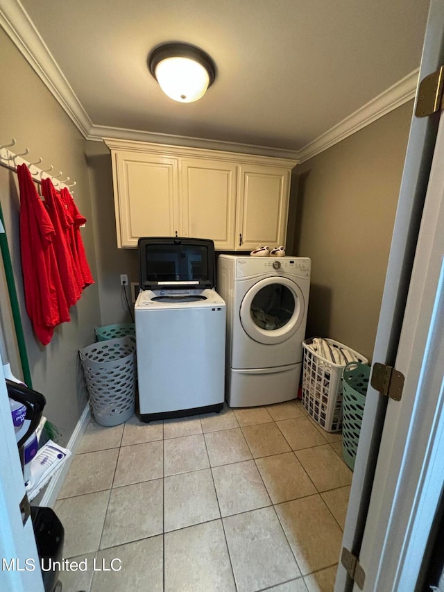 washroom featuring baseboards, light tile patterned flooring, cabinet space, ornamental molding, and washer and clothes dryer