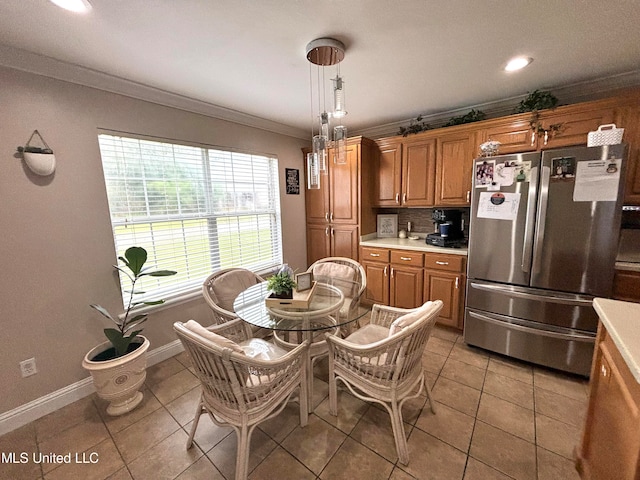 kitchen featuring backsplash, light countertops, ornamental molding, freestanding refrigerator, and brown cabinetry