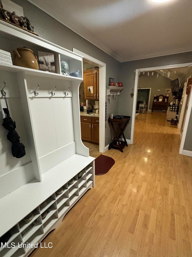 mudroom with baseboards, light wood-style floors, and ornamental molding