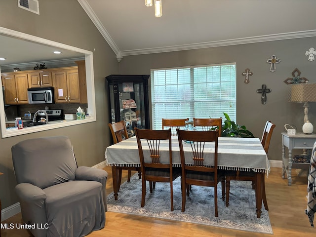 dining space featuring visible vents, baseboards, light wood-style flooring, and crown molding