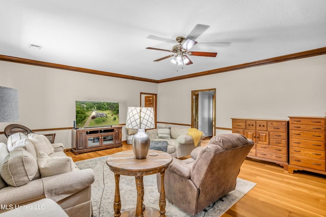 living room with a ceiling fan, ornamental molding, and light wood-style flooring
