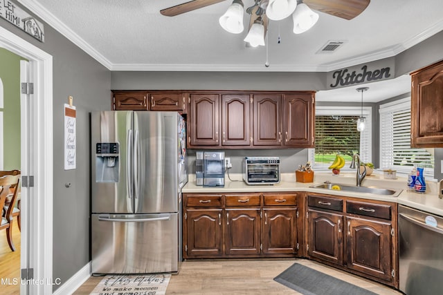 kitchen featuring appliances with stainless steel finishes, a sink, ceiling fan, light wood-type flooring, and ornamental molding