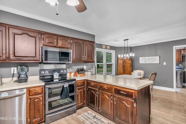 kitchen featuring stainless steel appliances, a peninsula, ornamental molding, light wood-type flooring, and light countertops